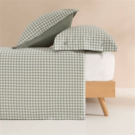 A Bed With Green And White Checkered Sheets Pillows And Pillow Cases On It