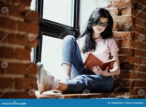 Beautiful Young Brunette Woman Reading Book Near Window At Home Stock