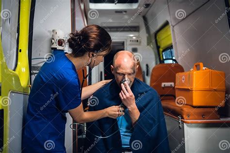 Nurse In Medical Uniform Puts Her Hand On Man Who Sits In Oxygen Mask