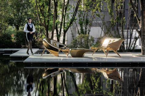 A Man Standing Next To Some Chairs Near The Water In Front Of Trees And