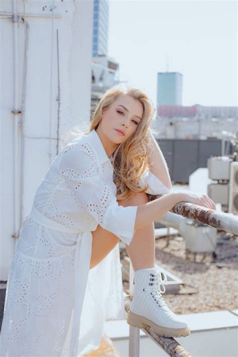 Charming Blonde In Snow White Dress And Long Loose Hair Poses On City Roof Walks Around City