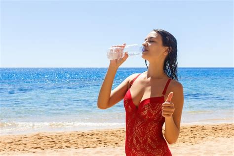 Premium Photo Beautiful Brunette Girl In Red Swimsuit Drinking Water On A Vacation Day