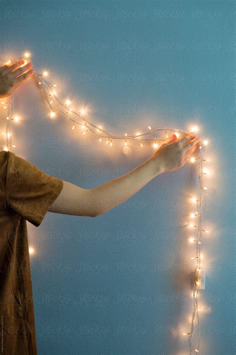 Crop Woman Hanging Garland On Wall Del Colaborador De Stocksy Danil