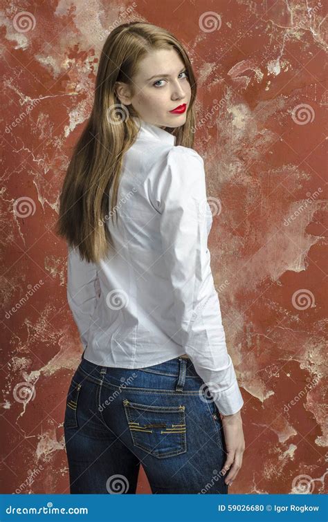 Jonge Slanke Mooie Jonge Blonde Vrouw Met Lange Benen En Haar In Tumultoverhemd En Jeans Stock