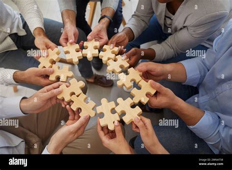 Business Team Holding And Connecting Parts Of Jigsaw Puzzle To Show