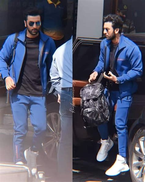 two men in matching blue outfits are exiting a vehicle and one is carrying a black bag