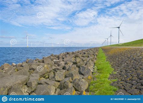 Parque E Lico En Un Lago A Lo Largo De Un Dique Debajo De Un Cielo Azul