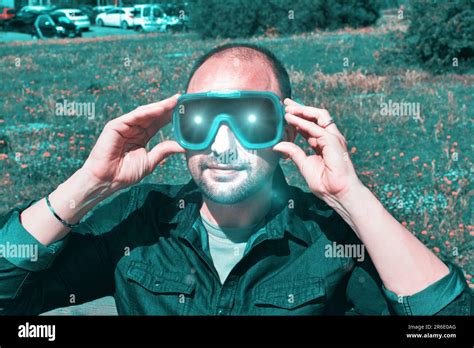 Young man in the nature wearing augmented reality glasses. Adult male having fun with AR glasses ...