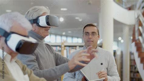 Elderly People In VR Glasses In Library With Teacher Side View Of