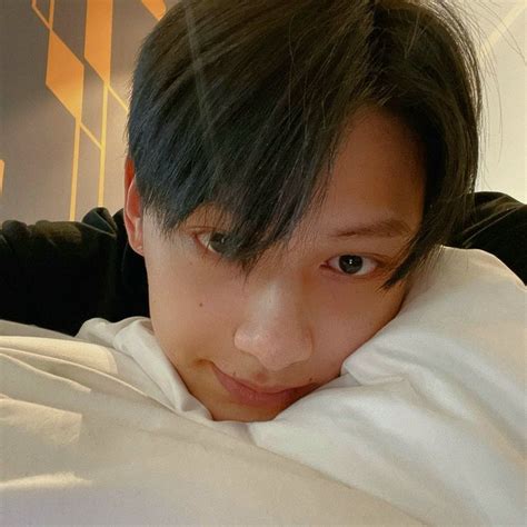 A Young Man Laying On Top Of A Bed Covered In White Sheets With His