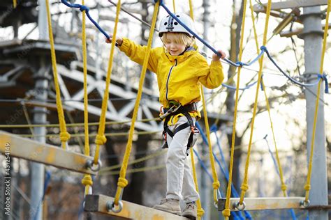 Little boy having fun in Adventure Park for children amoung ropes ...