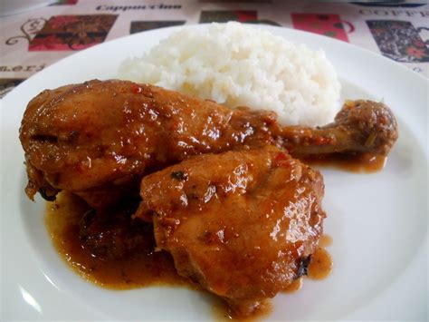 A White Plate Topped With Meat Covered In Gravy And Rice