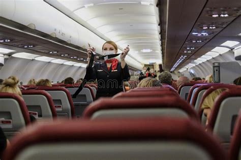 Stewardess In A Mask Demonstrates To Aircraft Passengers The Rules Of