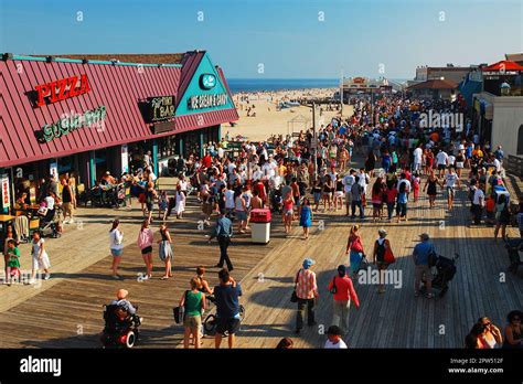 People Crowd The Boardwalk On A Beautiful Sunny Summer Vacation Day In