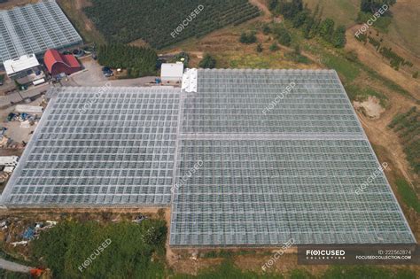 Aerial of futuristic glass roof of greenhouse in farmland. — structured ...