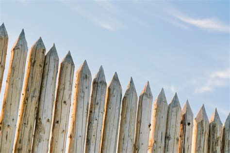 Premium Photo Fence Made Of Sharp Wooden Stakes Against The Blue Sky