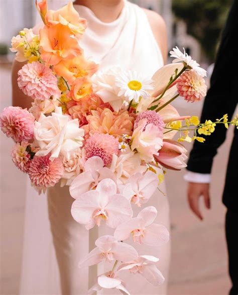 The Bride And Groom Are Walking Down The Street With Their Bouquets In