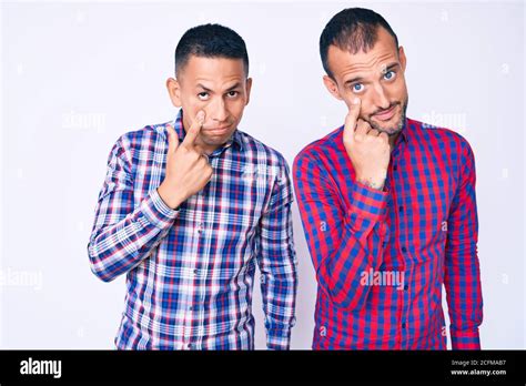 Jeune gay couple de deux hommes portant des vêtements décontractés pointant vers l œil vous