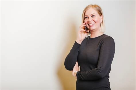 Blonde Frau stehend Betrieb Telefon lächelnd Kostenlose Foto