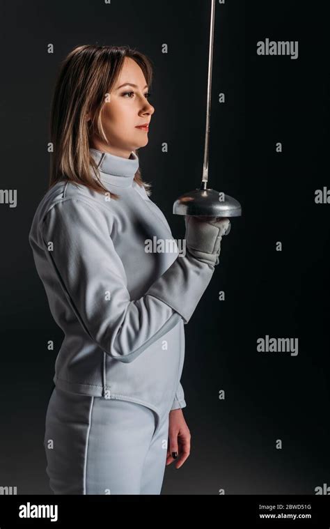 Side View Of Woman In Fencing Suit Holding Rapier Isolated On Black