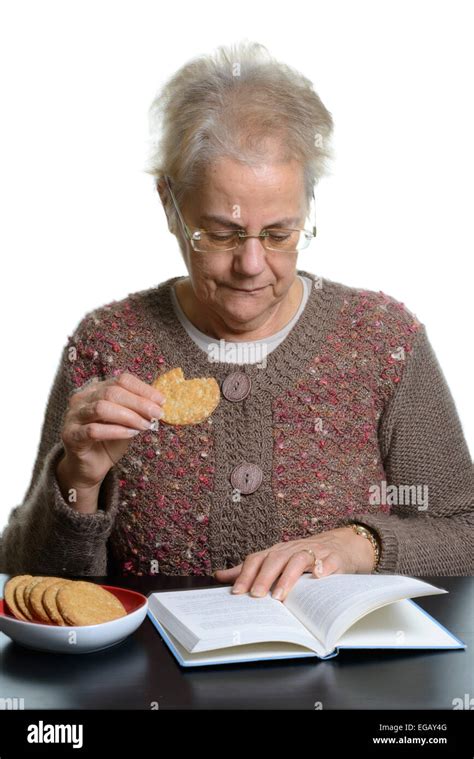 Mujer De Mediana Edad Leyendo Un Libro Mientras Come Galletas En Casa