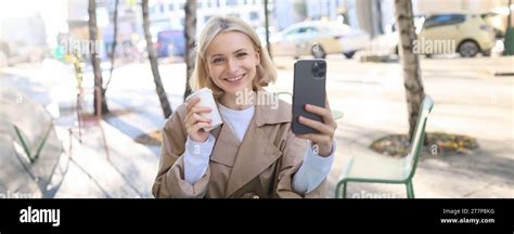 Belle jeune femme blonde posant avec tasse à emporter dans un café en plein air assis dans la