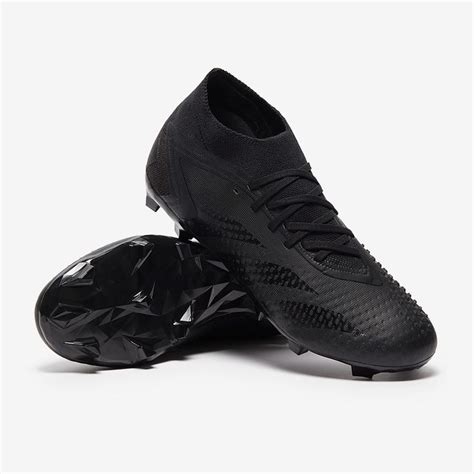 a pair of black soccer shoes sitting on top of a white floor next to ...