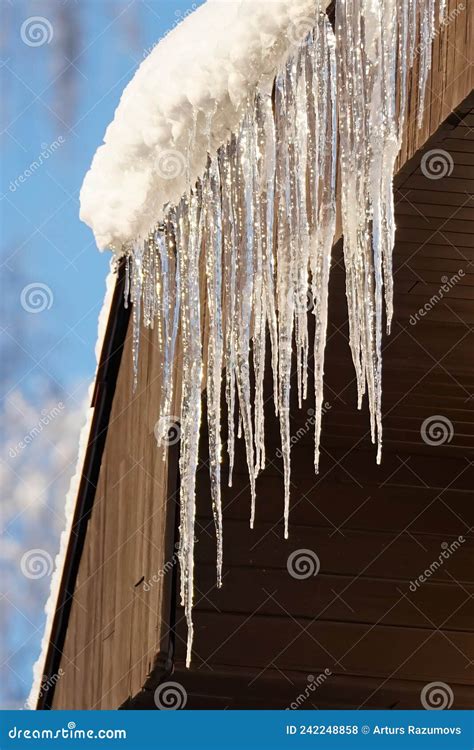 Icicles Hanging From The Roof On The Blue Sky Background Stock Photo