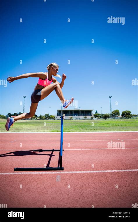 Female Athlete Jumping Above The Hurdle Stock Photo Alamy