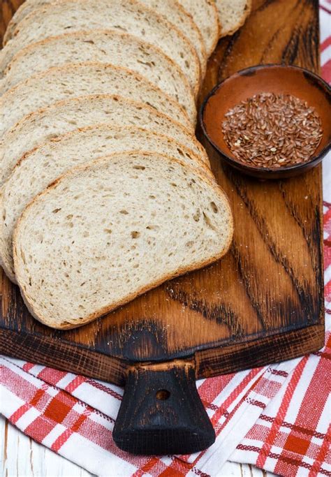 Rebanadas De Pan Entero Del Lino Del Grano En La Tajadera Imagen De