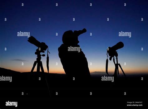 A Man Scours The Night Sky With Binoculars And Camera Equipment From