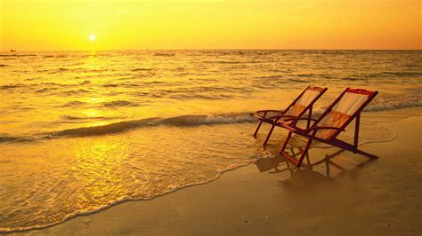 Two Wooden Chairs On Ocean Sand Waves During Sunset Yellow Sky ...