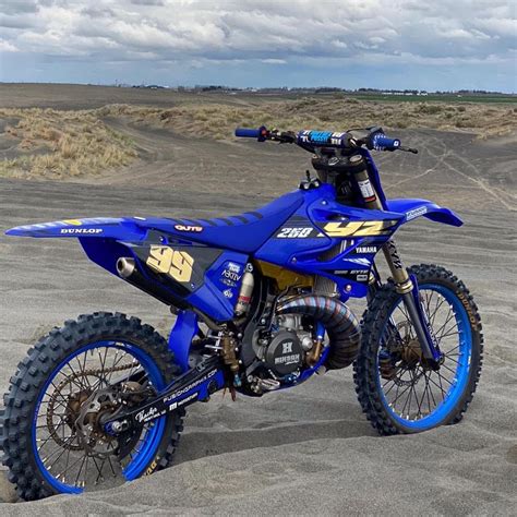 A Blue Dirt Bike Parked On Top Of A Sandy Field