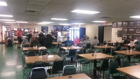 people are sitting at tables in a large room with lots of chairs and desks