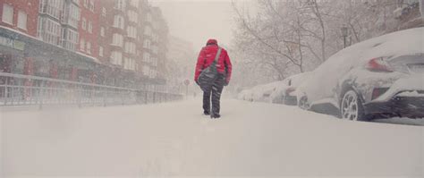 Woman Trudging Along Snow Covered Road Into The City Throught The Storm