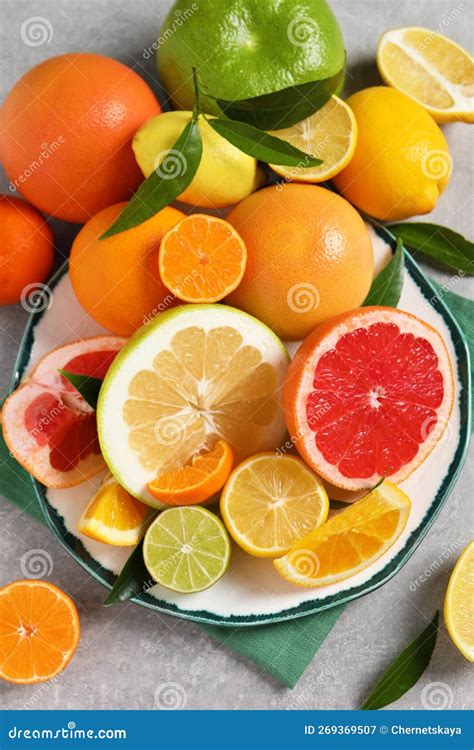Different Citrus Fruits With Fresh Leaves On Light Grey Table Flat Lay