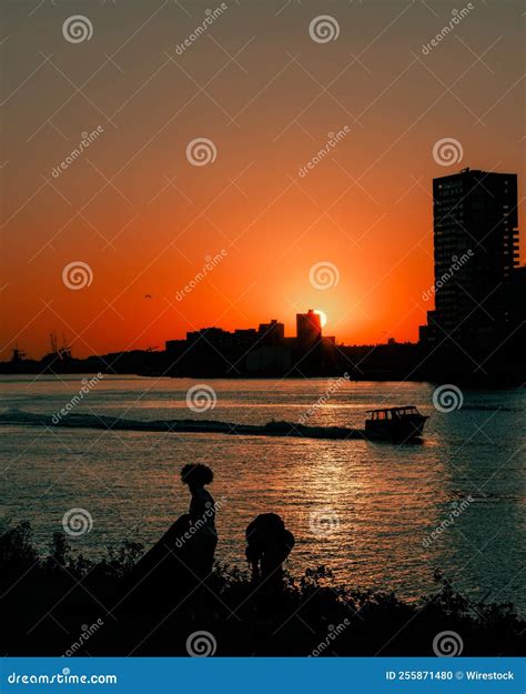 Dramatic Orange Sunset Over A Lake With The Silhouette Of People Stock