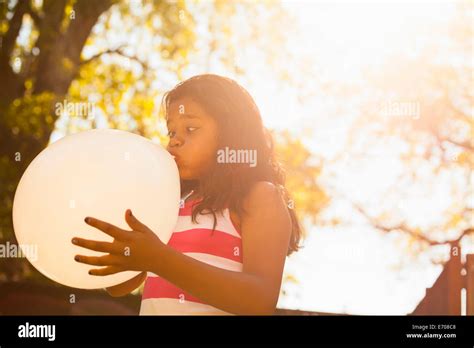 Girl blowing up balloon in garden Stock Photo - Alamy