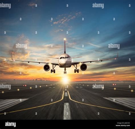 Passengers Airplane Landing To Airport Runway In Beautiful Sunset Light