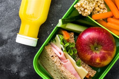 Caja de almuerzo escolar saludable con sándwich verduras frutas y