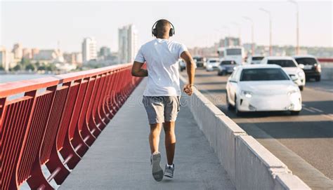 Well Fit African American Guy Running Down The Bridge Stock Photo