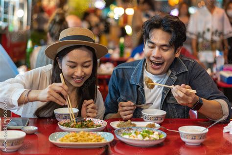 Foto de Young Asian couple traveler tourists eating Thai street food ...