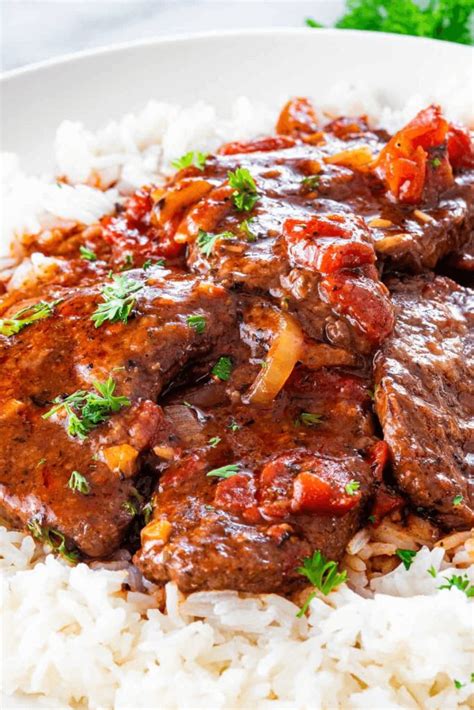 A White Plate Topped With Rice And Meat Covered In Gravy On Top Of It