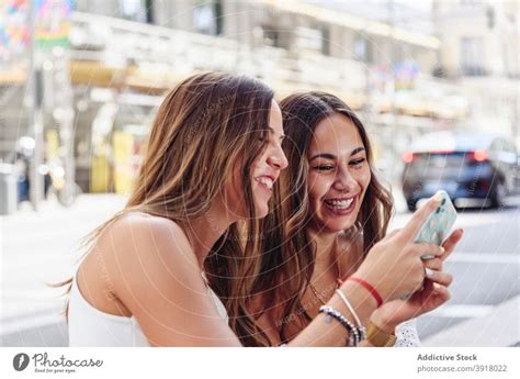 Laughing Girlfriends Using Smartphone On Street A Royalty Free Stock