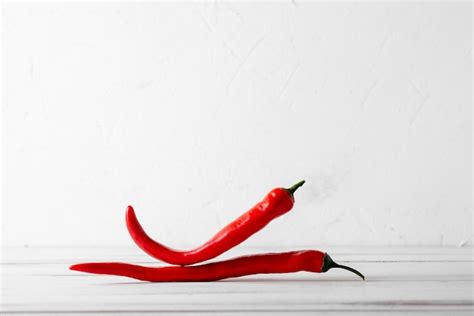 Premium Photo Red Hot Chili Peppers On A White Wooden Background