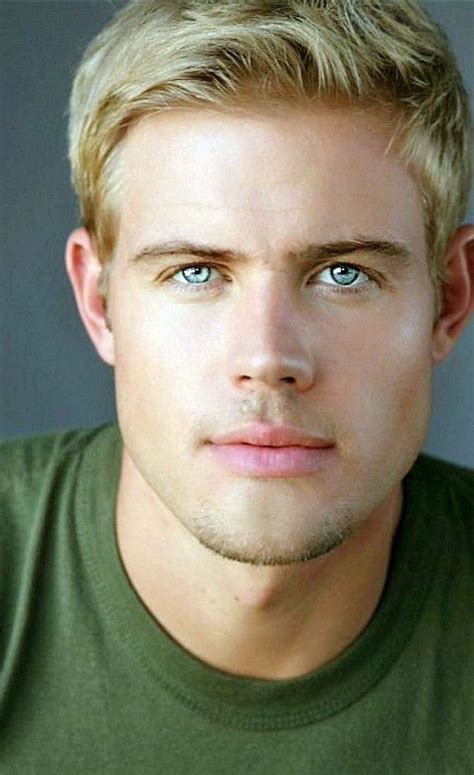 A Man With Blonde Hair And Blue Eyes Looks At The Camera While Wearing