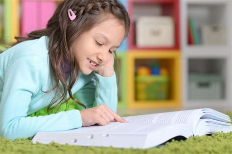 Premium Photo | Portrait of little girl lying on floor and reading book