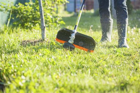 Worker Mows Green Grass On The Lawn With Hand Trimmer Lawn Care Weed