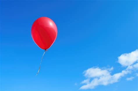 Premium Photo | A red balloon floating up towards a blue sky