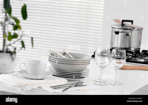 Stacked dishes and cutlery on table Stock Photo - Alamy